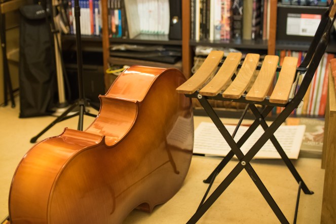 A cello lying on the floor by an empty chair